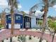 Charming blue two-story home with a red brick driveway, lush palm trees, and manicured landscaping at 931 Gulf Blvd, Belleair Beach, FL 33786