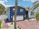 Two-story blue home with a two-car garage, brick driveway, white gravel landscaping, and exterior lanterns at 931 Gulf Blvd, Belleair Beach, FL 33786