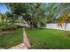 Spacious backyard with lush green grass, mature trees, and a brick pathway leading to the patio at 9674 104Th Ave, Largo, FL 33773