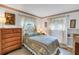 Comfortable bedroom with floral bedding, lace curtains, and wood dresser with soft lighting at 9674 104Th Ave, Largo, FL 33773