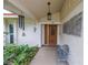 Inviting front entrance with a decorative wooden door, lush plants, and a cozy bench at 9674 104Th Ave, Largo, FL 33773