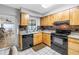 Functional kitchen boasting wood cabinets, granite countertops, black appliances, and tile floors at 9674 104Th Ave, Largo, FL 33773