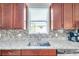 Close up of kitchen sink with granite countertops, tile backsplash, and stainless steel appliances at 10833 Breaking Rocks Dr, Tampa, FL 33647