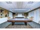 Brightly lit billiards room featuring two covered tables, comfortable seating, and elegant wall decor at 1210 Wolford Dr, Trinity, FL 34655