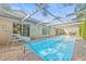 A sparkling pool with slide, covered by a screen enclosure, set in a brick patio, creating an outdoor retreat at 12222 Meadowbrook Ln, Hudson, FL 34667