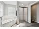 Bathroom featuring tiled tub, shower, and window with plantation shutters at 13227 Quigley Ave, Weeki Wachee, FL 34614