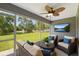 Cozy screened-in patio with wicker furniture, ceiling fan, and picturesque backyard views at 13227 Quigley Ave, Weeki Wachee, FL 34614