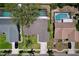 An aerial view showcases the home's roof, driveway, and the refreshing screened-in pool, surrounded by neighboring properties at 1445 Stonehenge Way, Palm Harbor, FL 34683