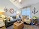 Comfortable living room with nautical decor, a plush sofa, an armchair, and ample natural light from the window at 1445 Stonehenge Way, Palm Harbor, FL 34683