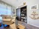 Comfortable living room showcasing nautical decor, a plush armchair, and a view of the shelving unit at 1445 Stonehenge Way, Palm Harbor, FL 34683