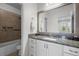 Bathroom featuring granite counters, large mirror, and shower-tub combo with tile surround at 14855 Renaissance Ave, Odessa, FL 33556