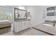 Bright bathroom featuring double sinks, a large mirror and stone countertops and views into the main bedroom at 14855 Renaissance Ave, Odessa, FL 33556