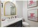 Stylish half-bath with marble countertop, gold hardware, arched mirror, and bright lighting at 15110 Kestrelglen Way, Lithia, FL 33547