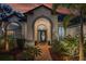 A charming front entrance with lush landscaping and a beautiful arched doorway, inviting guests inside at 15934 Sorawater Dr, Lithia, FL 33547