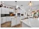 Modern white kitchen with marble countertops, stylish backsplash, and stainless steel appliances at 15934 Sorawater Dr, Lithia, FL 33547