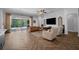 Spacious living room with herringbone wood floors, plush seating, and access to the outdoor patio at 15934 Sorawater Dr, Lithia, FL 33547