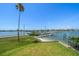 Waterfront backyard featuring lush grass, a dock, and picturesque views of the serene water at 16047 Redington Dr, Redington Beach, FL 33708