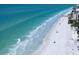 Elevated view of a white sand beach with clear ocean waters, with palm trees and buildings nearby at 16047 Redington Dr, Redington Beach, FL 33708