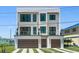 Contemporary home featuring a two-car garage, balcony, and artifical turf driveway at 16047 Redington Dr, Redington Beach, FL 33708