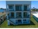 Modern three-story home featuring sleek lines, glass balconies, and well-maintained landscaping at 16047 Redington Dr, Redington Beach, FL 33708