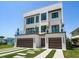 Striking modern home with a two-car garage, balcony, and manicured lawn at 16047 Redington Dr, Redington Beach, FL 33708