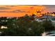 Beautiful sunset view of the water and nearby homes with lush greenery, tropical plants, and tall palms at 24197 Treasure Island Blvd., Punta Gorda, FL 33955