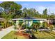 Charming home featuring bright shutters, lush tropical landscaping, and a well-manicured lawn at 2479 Trade Winds Dr, Dunedin, FL 34698