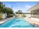Sparkling private pool surrounded by lush landscaping and a sunny sky at 2479 Trade Winds Dr, Dunedin, FL 34698