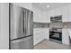 Modern kitchen featuring stainless steel appliances, white cabinetry, and a light gray backsplash at 323 48Th Nw St, Bradenton, FL 34209