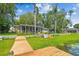 Rear exterior view featuring a large screened in lanai, waterfront access, and wooden dock at 3366 Clover Leaf Ln, Land O Lakes, FL 34639