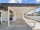 A covered carport with a white support structure, a black roof, and an entry door at 4215 E Paris St, Tampa, FL 33610