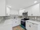 Updated kitchen featuring white cabinets, modern backsplash, and stainless steel appliances at 4215 E Paris St, Tampa, FL 33610