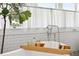 Close up of the white subway tile and freestanding tub featuring a wooden bath tray and plant at 4913 N Central Ave, Tampa, FL 33603