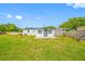 View of the home's backyard with healthy green lawn and a white-painted home at 5109 Horton Rd, Plant City, FL 33567