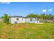 View of the home's backyard with healthy green lawn, mature trees, and a white-painted home at 5109 Horton Rd, Plant City, FL 33567