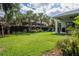 Large backyard featuring lush lawn, tropical landscaping, a playground, and covered patio at 5314 Alafia Falls Dr, Lithia, FL 33547