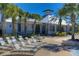 Community clubhouse featuring a white exterior, palm trees, landscaping, and lounge chairs at 5314 Alafia Falls Dr, Lithia, FL 33547