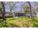 Expansive backyard showing the home's exterior, a screened-in porch, and a neatly kept lawn, all set under mature trees at 6114 7Th S Ave, Gulfport, FL 33707