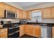 Well-lit kitchen featuring wood cabinets, stainless steel appliances, and dark countertops at 6114 7Th S Ave, Gulfport, FL 33707