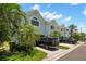Stylish condo exterior featuring a well-maintained lawn, shrubs, and mature palm trees at 616 Garland Cir, Indian Rocks Beach, FL 33785
