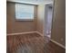 Cozy bedroom with wood-look floors and a window, adjacent to the bathroom at 6434 Old Main St, New Port Richey, FL 34653
