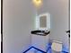 Modern half-bathroom featuring a sleek vanity with an illuminated mirror, a toilet, and upscale marble flooring at 6522 Simone Shores Cir, Apollo Beach, FL 33572
