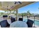 A covered outdoor seating area has a table and four chairs overlooking the pool and waterway at 6522 Simone Shores Cir, Apollo Beach, FL 33572