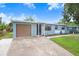 View of blue house with attached garage, a concrete driveway, manicured lawn and adjacent street in a neighborhood at 660 11Th N Ave, Safety Harbor, FL 34695
