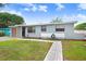 An eye-level view of a single-story home, showcasing its blue exterior, a well-kept lawn, and a quaint, paved walkway at 660 11Th N Ave, Safety Harbor, FL 34695