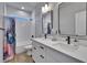 Bathroom featuring double sinks, dark hardware, mirrors, and a colorful shower curtain at 7203 1/2 S West Shore Blvd, Tampa, FL 33616