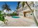 Spacious backyard showcasing a pool, spa, travertine patio, and a private boat dock on the water at 803 Harbor Dr, Belleair Beach, FL 33786