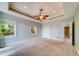 Bright bedroom with a tray ceiling, ceiling fan, neutral paint, and carpet at 803 Harbor Dr, Belleair Beach, FL 33786