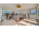 Open loft area with hardwood floors, large windows offering natural light, and staircase with decorative metal railing at 803 Harbor Dr, Belleair Beach, FL 33786