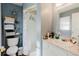 Well-lit bathroom with a toilet, shelving, and shower with white tile and blue accents at 8517 N Branch Ave, Tampa, FL 33604